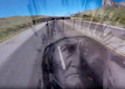 Geronimo overlaid on road with Orange & Black motorcycles in the background